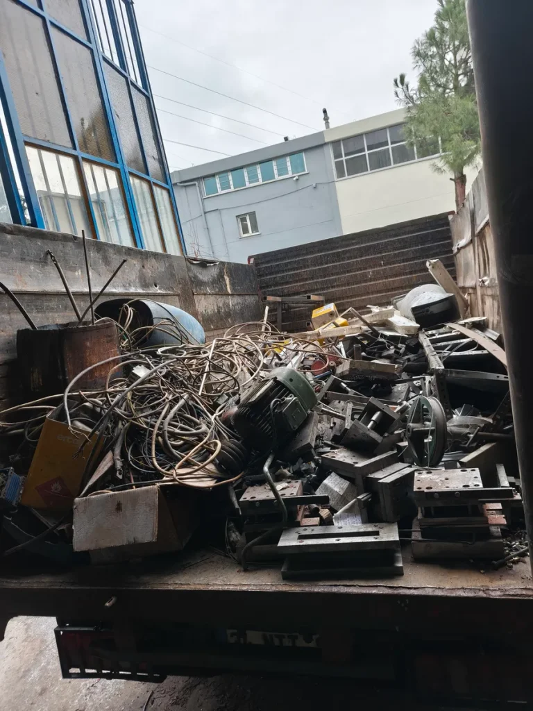 Kamyon kasasında toplanmış karışık hurda: kablo, elektrik motoru ve çelik kalıp parçaları